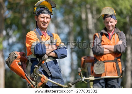 Happy garden workers with petrol string trimmers outdoors