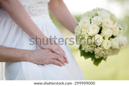 Wedding day: young married couple holding hands and flower bouquet