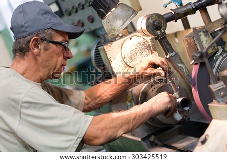 Factory worker measure detail with digital caliper micrometer during finishing metal working on lathe grinder machine