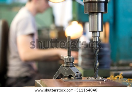 metal cutting hole boring on vertical drilling machine with machining drill tool at factory workshop background