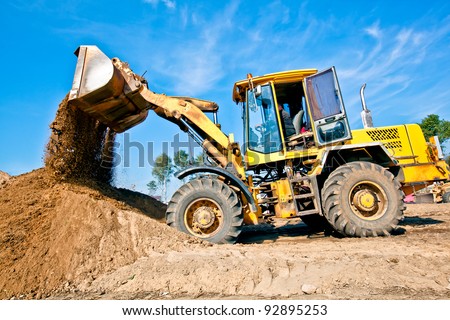 Wheel loader machine unloading soil during earthmoving works at construction site