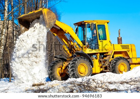 Construction and snow removal equipment at work - wheel loader  unloading snow during roadworks