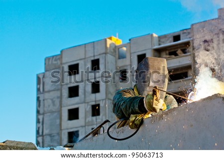 Industrial worker welder during installation of house wall panels using blind welding machine