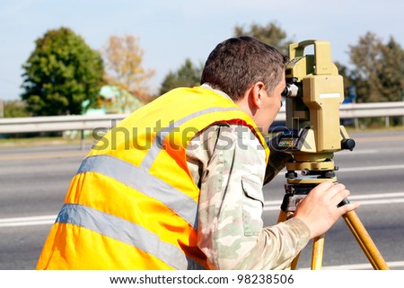 Surveyor engineer making measuring at highway with optical equipment theodolite