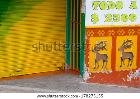 A closed shop in Guatape, Colombia. (Every shop or house has tiles along the facade\'s lower walls in bright colors and dimensioned images)