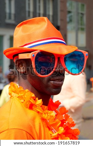 AMSTERDAM, THE NETHERLANDS, APRIL 26, 2014: A man dressed in orange on Holland\'s first King\'s day (Koningsdag), celebrating King Willem Alexander\'s birthday on April 26, 2014