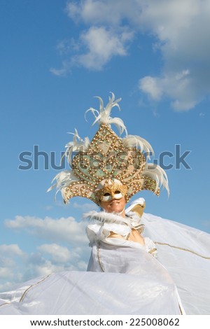 LOOSDRECHT, THE NETHERLANDS, MAY 24: Unidentified Venetian masked lady against a partly clouded sky during an open air event on May 24, 2014 in Loosdrecht, Holland.