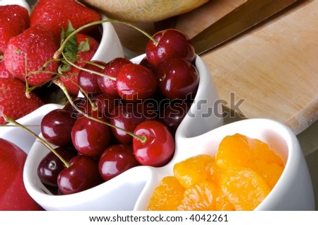 Small white bowls of cherries, strawberries, and orange slices.