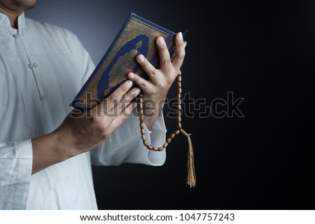 Muslim man read Quran isolated in black background
