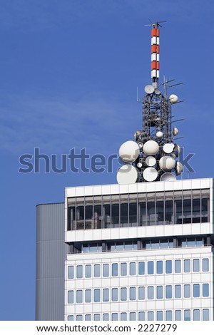 Cluster of different microwave antennae on top of a high rise modern office building