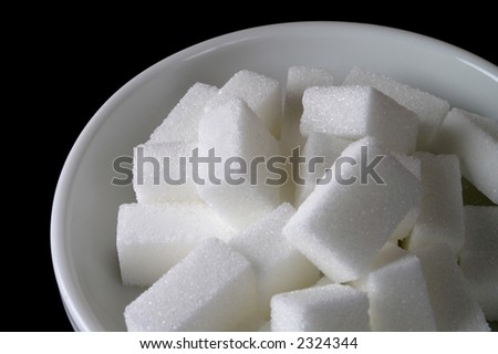 White ceramic sugar bowl with sugar cubes in black background (closeup)