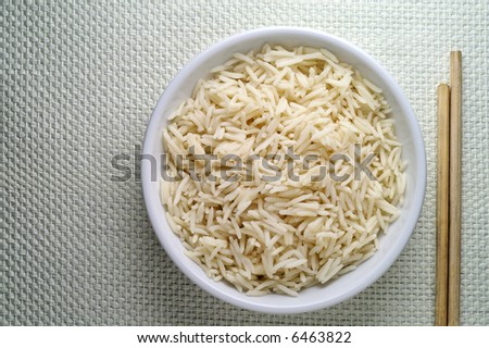 Dish of Basmati rice and chopsticks seen from above over linen tablecloth