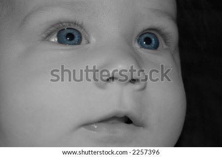 Close-up of face of four month old baby.  Black and white with eyes left blue.