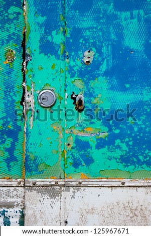 Detail of brightly coloured peeling paint on old car door