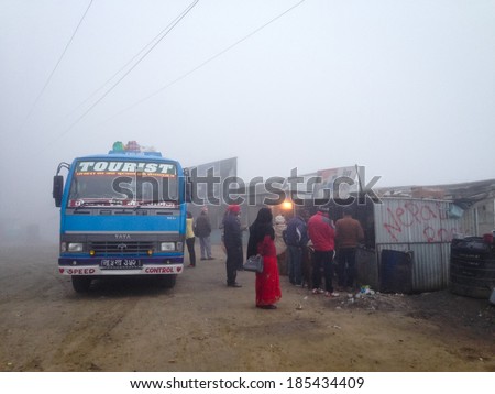 Dumre, Nepal - 5 February 2014: A long-distance bus from Pokhara to Nepalgunj takes an early morning tea stop in the fog at roadside stalls near Dumre.
