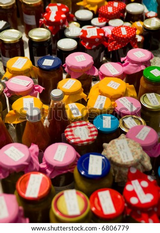 Colorful jars of home-made preserves and sauces at market stall, photographed with shallow depth of field with focus in center
