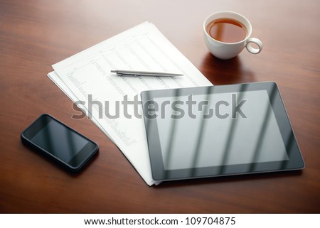 Modern workplace with digital tablet computer and mobile phone, pen and papers with numbers.