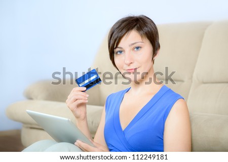 Young woman sitting with digital tablet and holding a credit card.