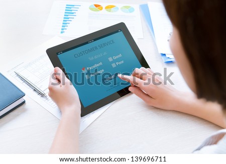 Businesswoman Holding Modern Digital Tablet With Customer Service Survey Form On A Screen. Red Tick On Excellent Choice Showing Customer Satisfaction