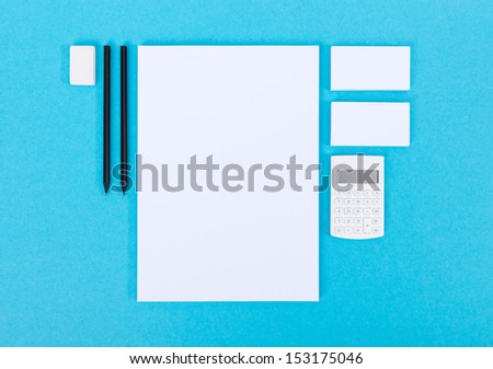 Set of variety blank office objects organized for company presentation or branding identity. Isolated on blue paper background.