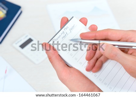 Business person thinking and writing new planning to-do list in schedule checklist book for the next year with ballpoint pen in the office.