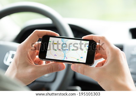 KIEV, UKRAINE - MAY 16, 2014: Man in the car planning a route using a Google Maps application on Apple iPhone 5S. Google Maps is a most popular web mapping service for mobile provided by Google inc.