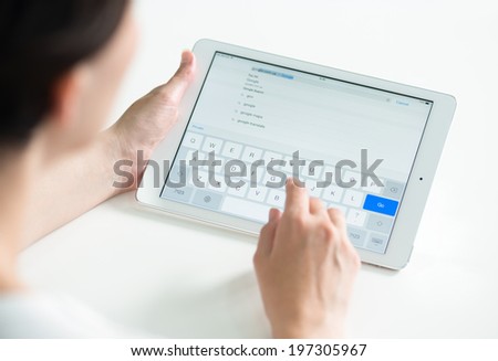 KIEV, UKRAINE - MAY 21, 2014: Woman holding a white Apple iPad Air and typing for search Google web page in Safari browser. The Google search most used web page in the world, owned by Google inc.