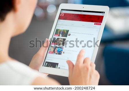KIEV, UKRAINE - MAY 21, 2014: Woman holding a brand new Apple iPad Air and looking on YouTube music playlist on a screen. YouTube is the popular video-sharing website that founded in February 14, 2005