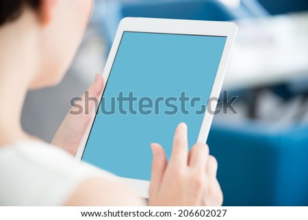 Woman holding and touching on a modern digital tablet and looking on a blank screen.