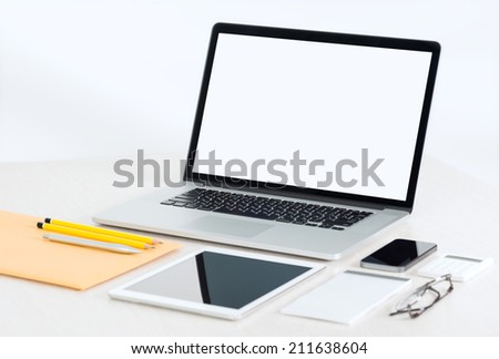 Modern office workplace with metallic laptop, digital tablet, mobile phone, papers, notepad and others business objects and items lying on a desk. Isolated on white background.