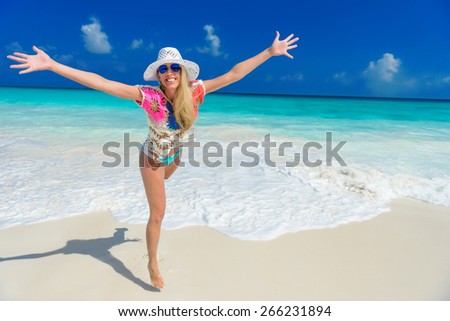 long haired blonde woman with flower in hair in bikini on tropical beach