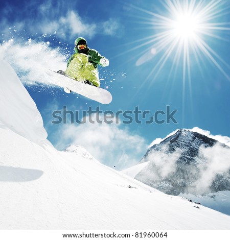 Snowboarder at jump inhigh mountains at sunny day.