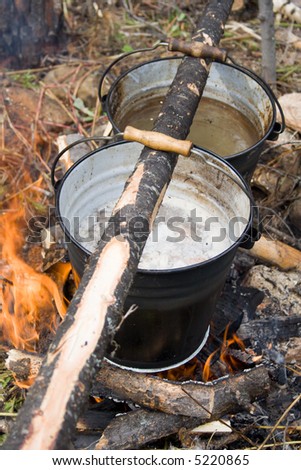 Boiling water in pails above the fire in camping