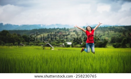 young woman happy jumping on cornfield in raining season, pretty girl relaxing outdoor