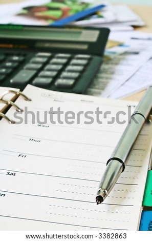 close up of pen and daily planner with bills on the background