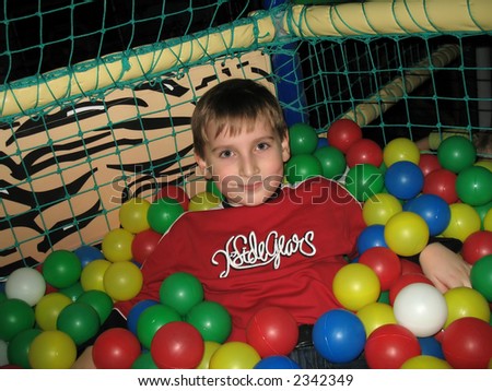Boy in the playground basket with lot of plastic balls