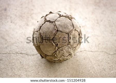 Old used football or soccer ball on cracked asphalt