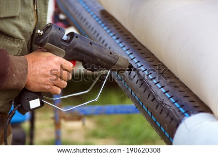 Worker fixing filter paper on perforated pipe with hot plastic glue gun