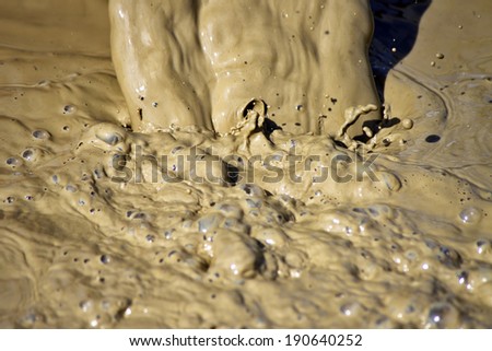 Close up of muddy water waste flowing as process of drilling water bore or well