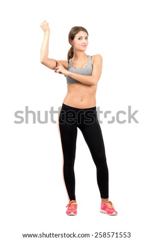 Young sporty woman flexing arm biceps muscle. Full body length portrait isolated over white background.