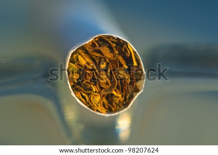 Shallow depth of field high magnification macro shot of tobacco leaves in the cigarette in the glass ashtray.