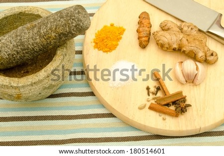 Traditional cooking ingredients on wooden chopping board and stone mortar