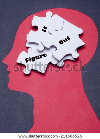 Jigsaw puzzle pieces and black paper project as a outline of human head: Figure it out text