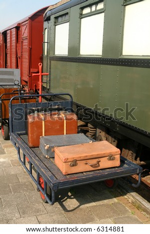 Vintage suitcases on trolley at the train-station with old traincars in the background