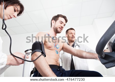 Doctor and nurse assist the patient during the medical examination of cardiac stress test