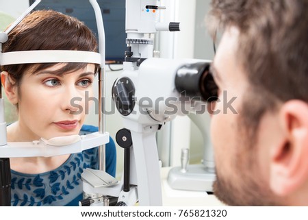 Beautiful woman having an eye exam with slit lamp\
/ Ophthalmologist in eyes clinic doing an exam diagnostic with vision of patient by modern computer systems - high technology concept and eyes care