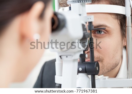 Slit Lamp eye control with the Ophthalmologist / handsome man during a contact lenses examining/ the oculist in eyes clinic doing cornea and retina exam diagnostic / high technology concept eyes care