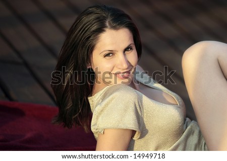 beautiful woman smiling with her leg close to her face and sun shinning over her