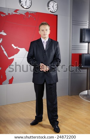 full length business man standing up in front of the camera in television news studio