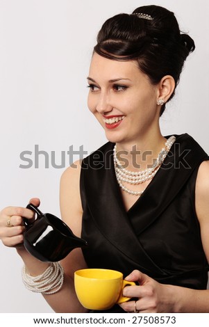 Stylish smiling lady serving tea at breakfast in a classic looking dress isolated on white background